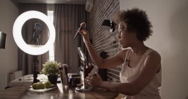 Siyah kadın evde canlı yayında makyaj yapıyor.