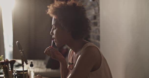 美しいですVlogのために家でビデオを撮影しながら アフリカ系アメリカ人女性の静的ショットでミラーとスミアリップグロスオン唇 — ストック動画