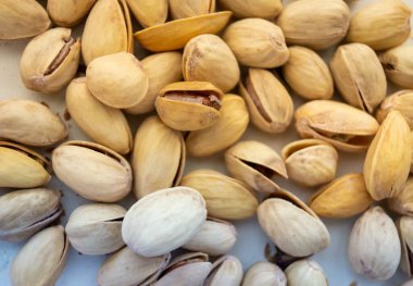 Beyaz arka planda rastgele dağılmış bir sürü fıstık.