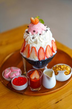 Tahta bir masaya yerleştirilmiş çilek bingsu.