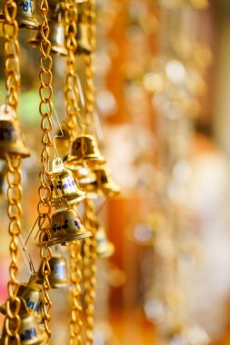 Zincirde asılı altın çanın bulanık bir arka planı var..