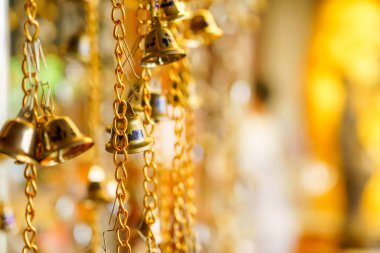 Zincirde asılı altın çanın bulanık bir arka planı var..