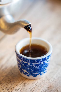 Çay çaydanlığın fayanslı bardağına dökülüyor..