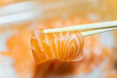 Bulanık bir arka planda çubuklarla çimdiklenmiş somon balığı.