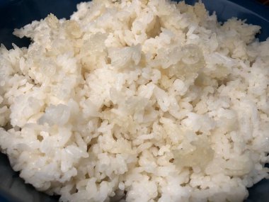 Mavi arka planda kaşıklı beyaz pirinç.