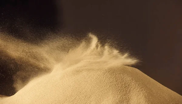 Sand flying explosion over dark background