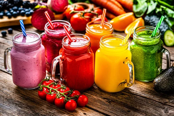 Healthy rainbow colored fruits and vegetables smoothies on rustic wooden