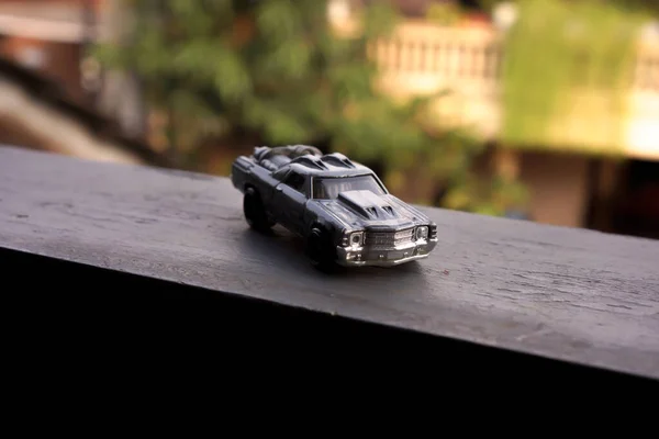 Beton platformda arka planı bulanık gri oyuncak araba.