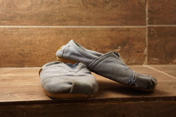 Ahşap merdivendeki açık mavi ayakkabılar üzerinde eski kirli bir kayış.
