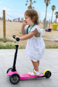 Little girl, playing with her scooter in the street