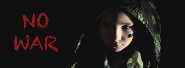 грустный ребенок с раскрашенным украинским флагом на щеке рядом нет войны буквы на черном, баннер