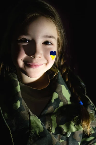 Enfant souriant avec drapeau ukrainien peint sur la joue isolé sur noir — Photo de stock