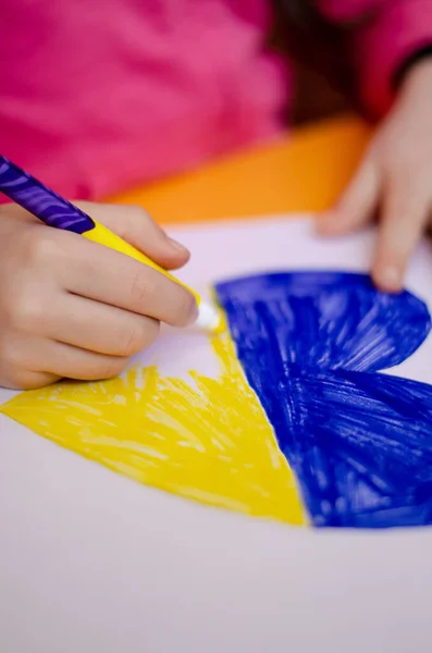 Vista ritagliata del cuore disegno bambino con bandiera ucraina sulla scrivania gialla — Foto stock