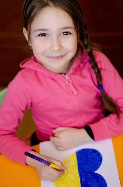 High angle view of cheerful kid drawing heart with ukrainian flag colors on paper — Stock Photo