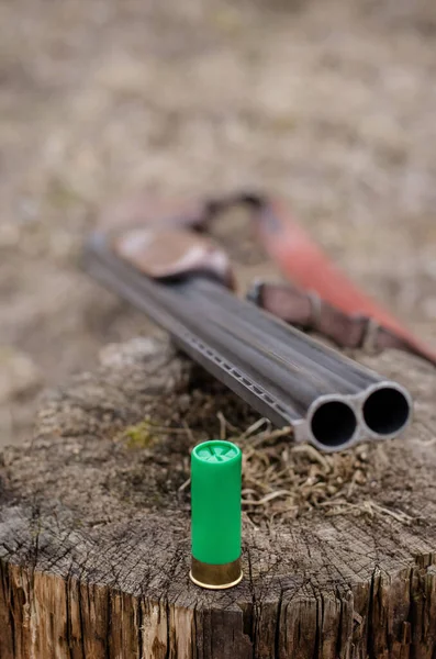 Close up de rifle perto de espingarda shell no toco de madeira — Fotografia de Stock