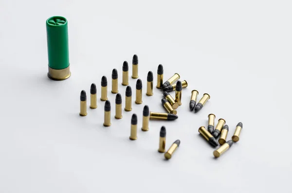 Same caliber bullets near shotgun shell on white — Stock Photo