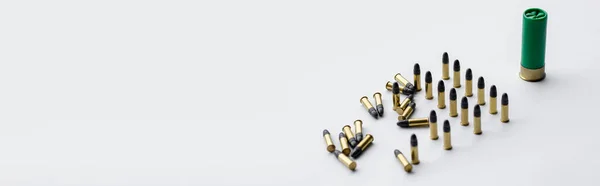 Same caliber bullets near shotgun shell on white, banner — Stock Photo