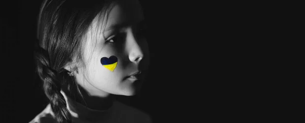 Monochrome photo of frustrated girl with painted ukrainian flag on cheek isolated on black, banner — Stock Photo