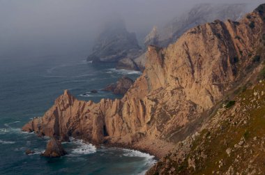 Cape Roca (Cabo da Roca, Portekiz) ve Atlantik Okyanusu 'nun yükselen fırtına dalgaları üzerine sis iner.