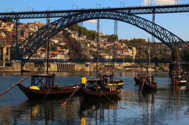 Douro nehri üzerindeki Ponte I. Luis Köprüsü ve Portekiz 'in kuzeyinde Porto şehrinde şarap fıçıları olan tipik Portekiz tekneleri.