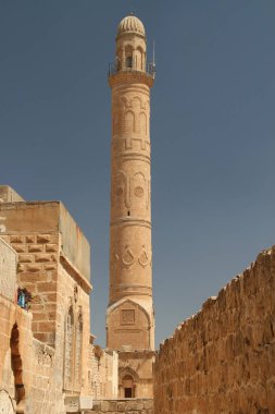 A view of the high ornate minaret of the Mardin Grand Mosque from a narrow street in the historic part of the city of Mardin in the Southeast Anatolia region of Turkey