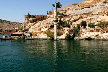 Güneydoğu Türkiye 'nin Halfeti ilinin tarihi kesiminde kayalar, Fırat nehri ve sular altında kalan Halfeti Batik Camii camiinin minaresi manzaralı