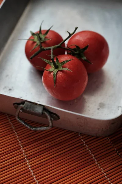a branch of fresh tomatoes in a metal dish