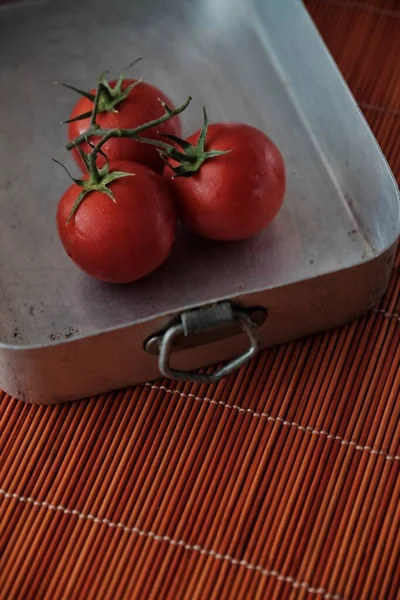 a branch of fresh tomatoes in a metal dish