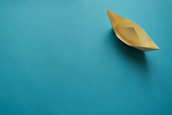 yellow origami paper boat on a blue background