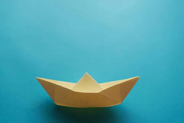 yellow origami paper boat on a blue background