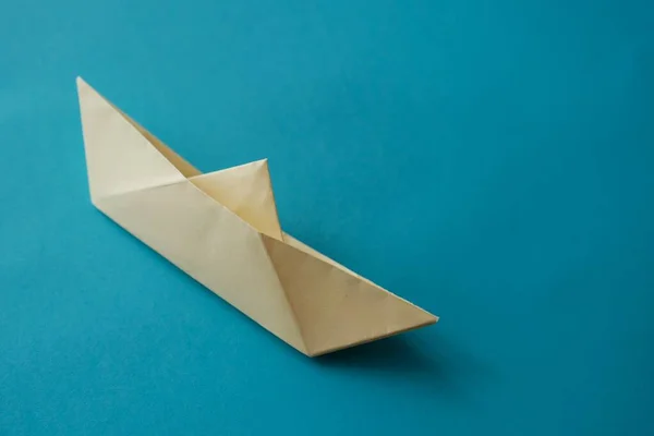 yellow origami paper boat on a blue background