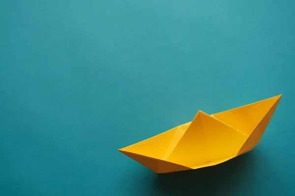 yellow origami paper boat on a blue background