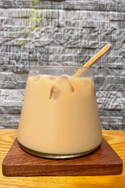 Cam fincanda buzlu latte kahve, ahşap tabağa konur.