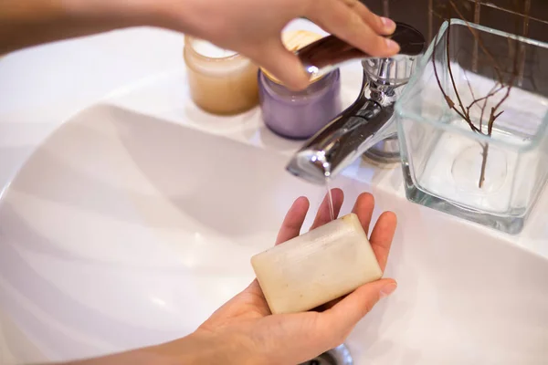 Closeup on young woman hands with soap bar washing hand