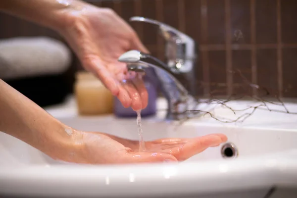 woman wash their hands in a sink with foam