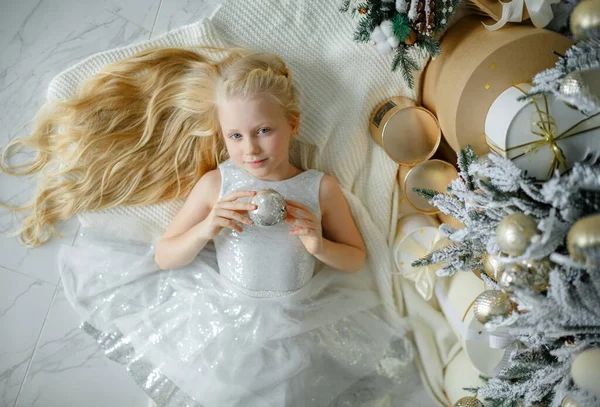 Okouzlující Malá Blondýnka Stříbrných Šatech Leží Blízkosti Vánočního Stromečku Horní Stock Fotografie