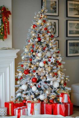 Evin içinde kırmızı ve beyaz tonlarda Noel ağacı, hediyeler ve ışıklarla