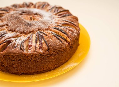 Charlotte elmalı turta, sarı tabakta pudra şekerle kaplanmış olarak evde pişirilir.