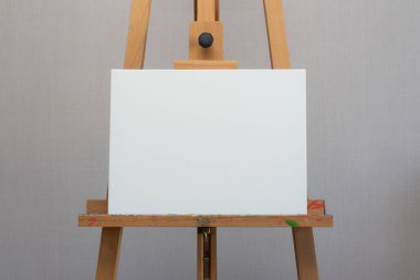 Boş beyaz tuval, ahşap sehpanın üzerinde duruyor.