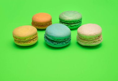 Beş farklı renkte makarna seti yeşil arka planda yan yana yatıyordu.