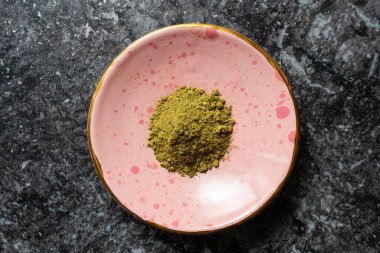 Yeşil kratom tozu yığını küçük bir seramik gül tabağı içinde sırt kayalık desen fotoğraf üst düz yatıyordu