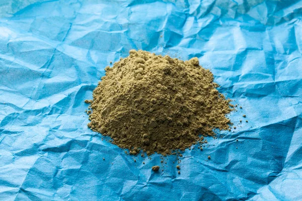 Mavi kramplı kağıt zemin üzerinde yeşil pudralanmış kratom yığını