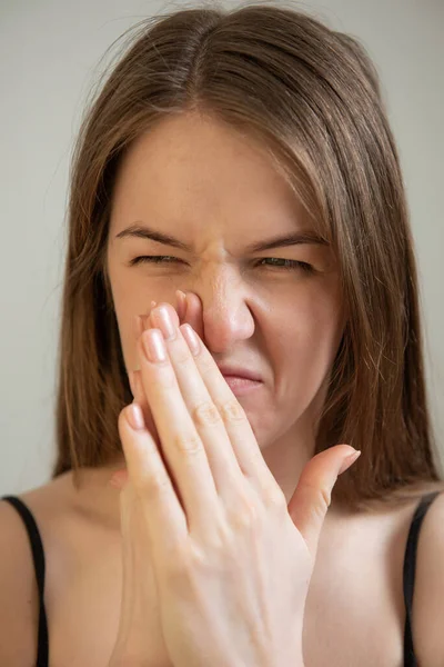 young female feels bad smell expressive face
