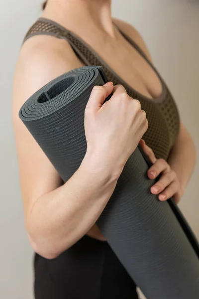 Kız gri yoga minderini tutuyor. Fotoğrafı kapat. Yüz yok.