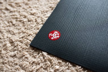 Gri paspas köşesinde Manduka yoga minder şirketi logosu.