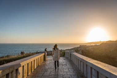 Cascais, Portugal - 2018, May 14th - tourists walking in a rocky path in Cascais area to see the sunset in the sea