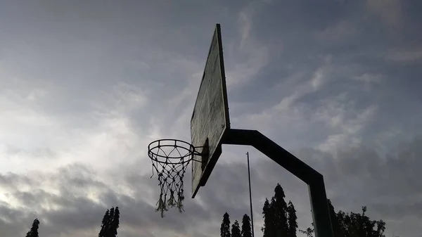 公共运动场上浅绿色旧篮球圈和蓝天破网的前背角景观 — 图库照片
