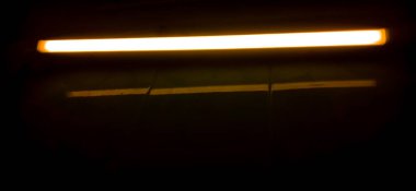 Duvara monte edilmiş floresan tüpünün ayrıntıları, sahte sarı ışık.