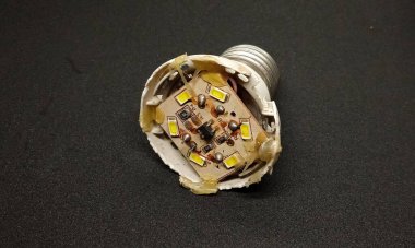 Kırık beyaz LED lambanın içindeki devre, siyah arka planda izole edilmiş. Kırık beyaz lamba devreleri. Kırık ışık bileşenleri.