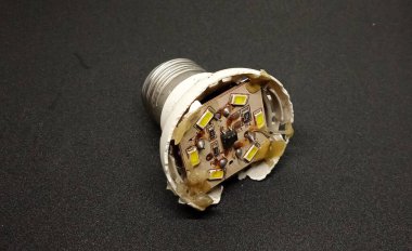 Kırık beyaz LED lambanın içindeki devre, siyah arka planda izole edilmiş. Kırık beyaz lamba devreleri. Kırık ışık bileşenleri.